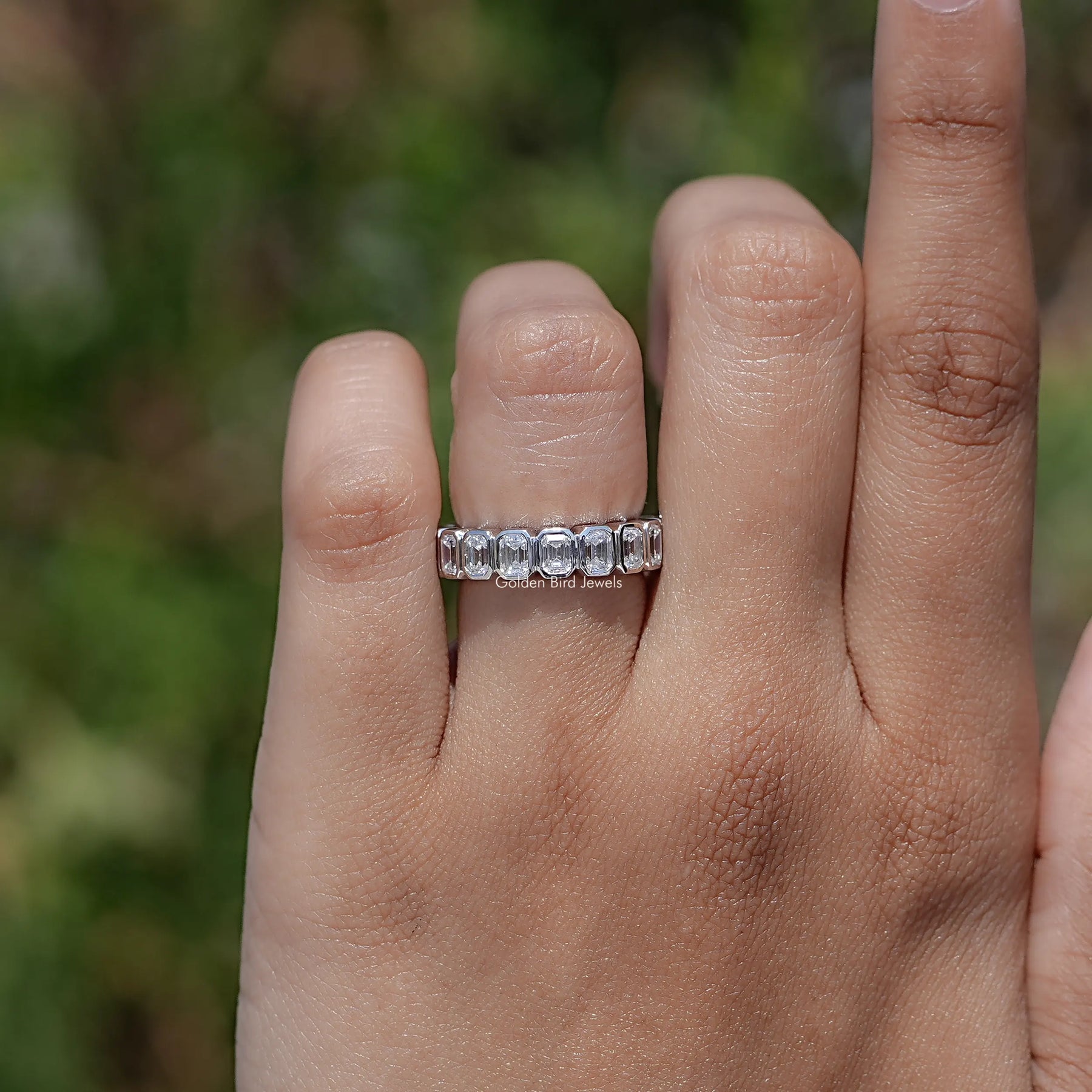 In finger view of Bezel Set Emerald Cut Full Eternity Band