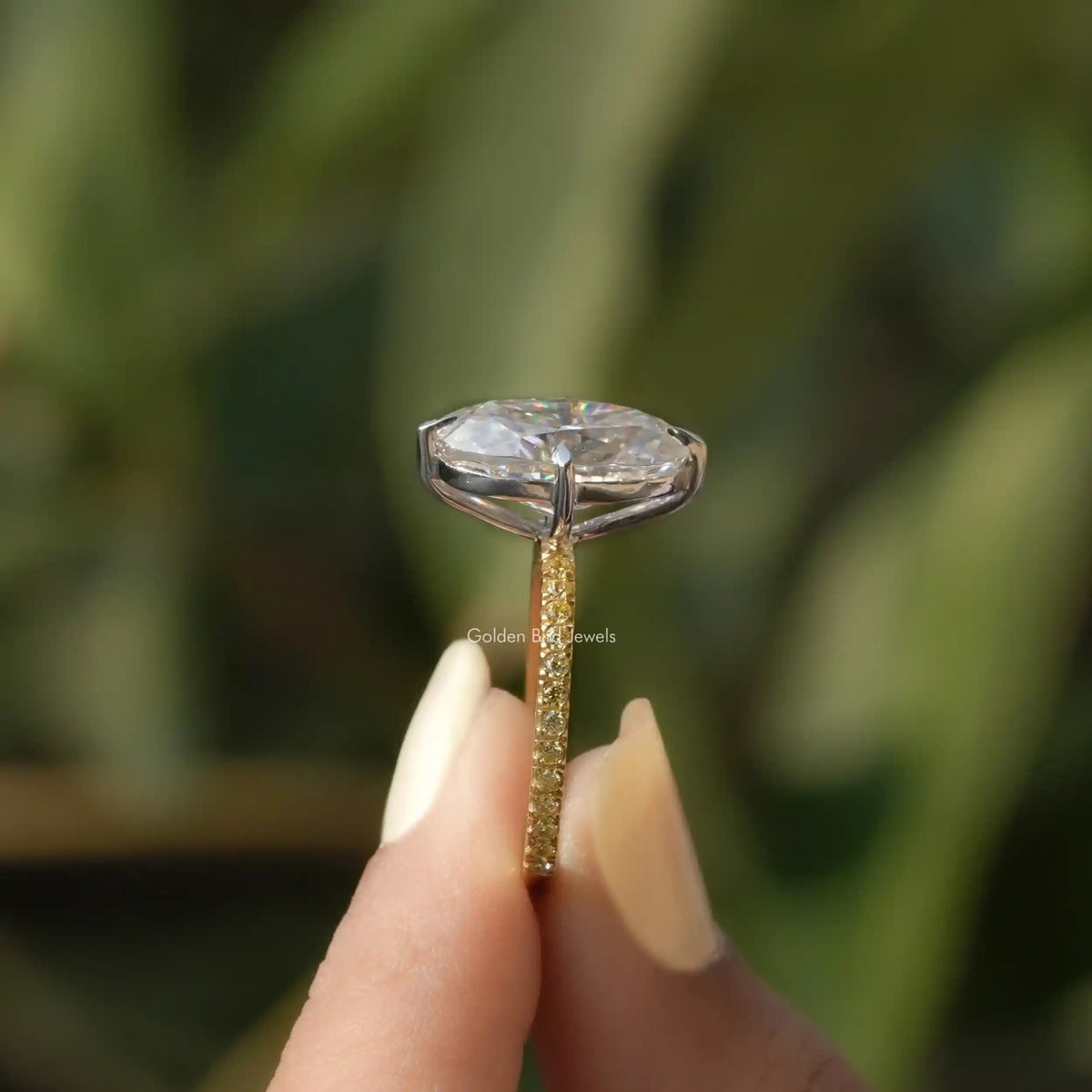 Side View of Oval Cut Moissanite Accent Stone Ring In two fingers