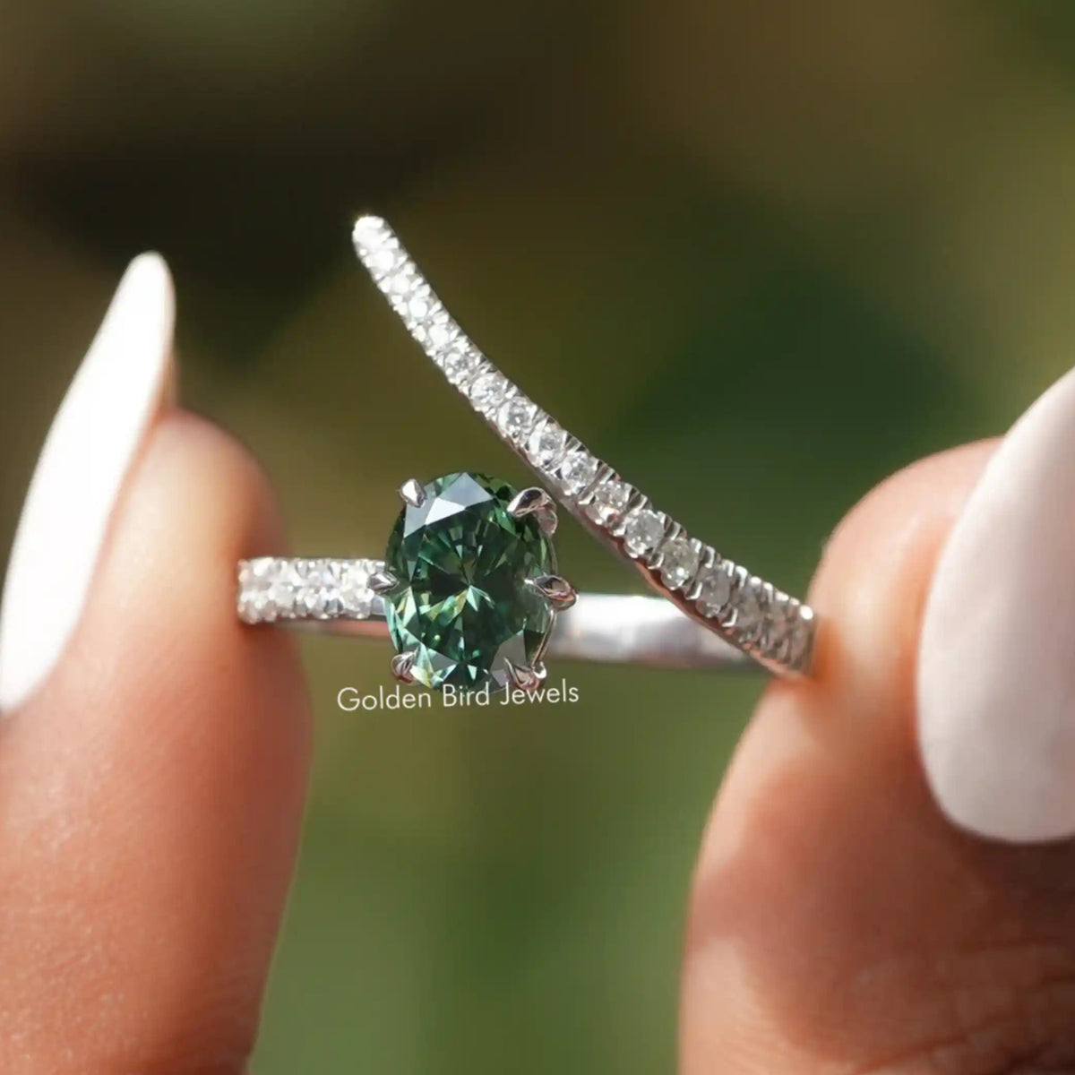 Two fingers holding the Dark Green Oval Cut Moissanite Accent Stone Ring