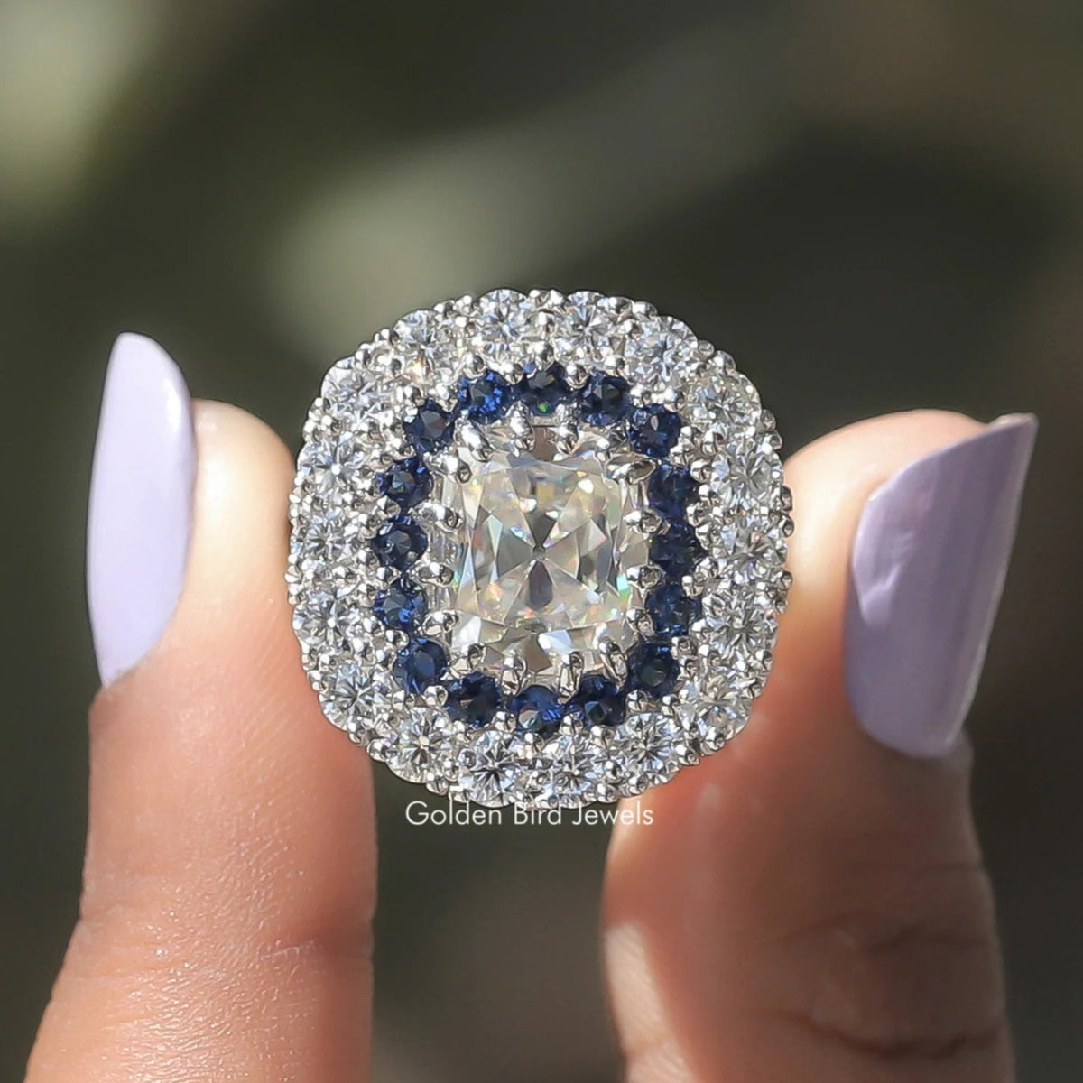 Two fingers holding the Double Halo Old Mine Cushion Cut Moissanite Ring