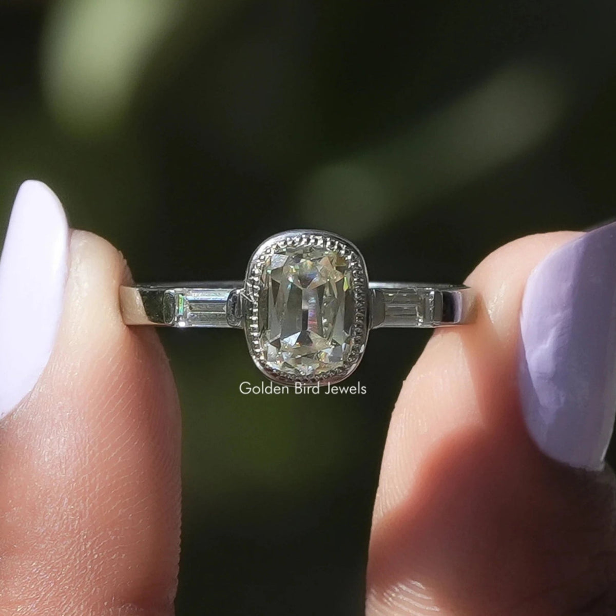 Two fingers holding the Old Mine Cushion Cut 3 Stone Moissanite Ring