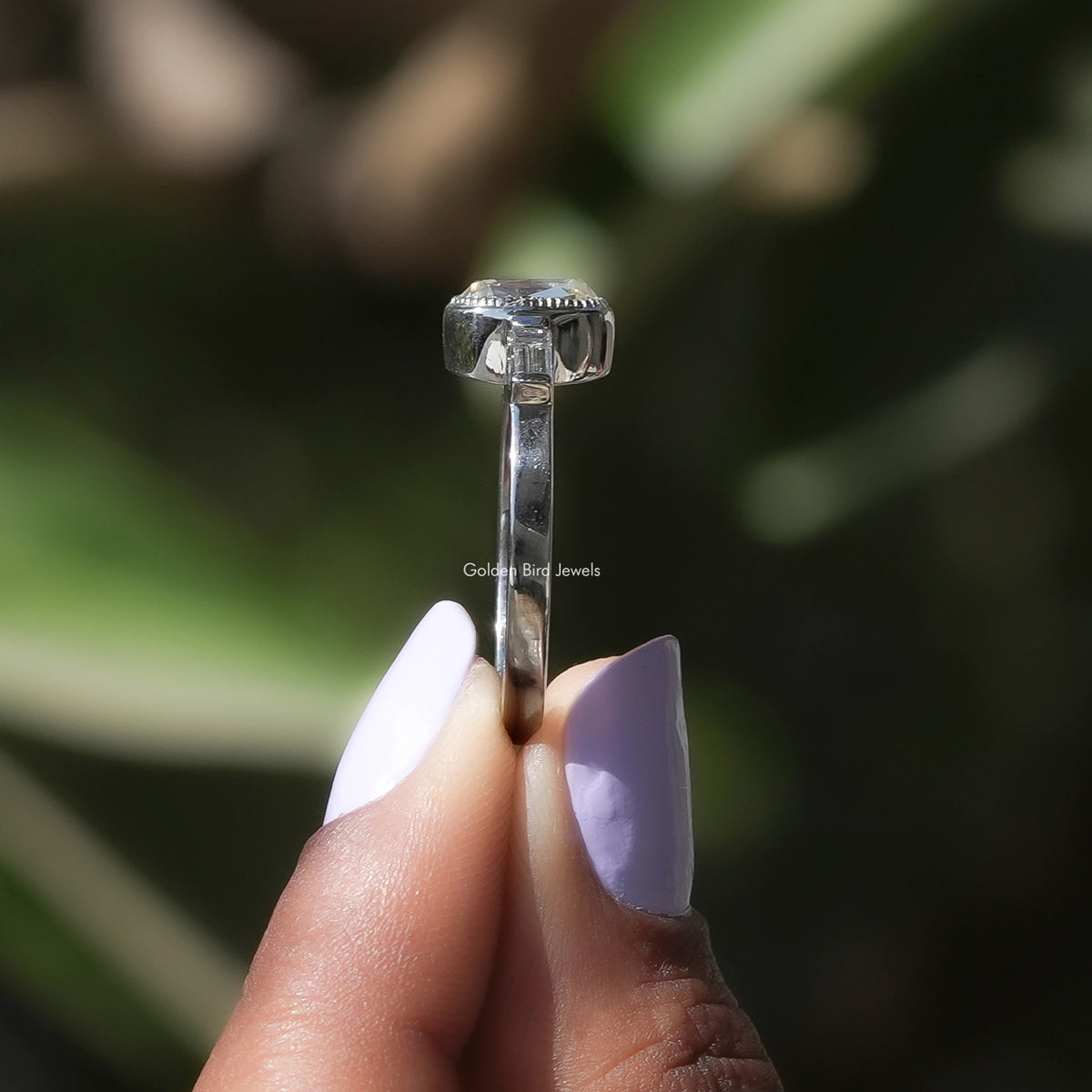 Side View of A Cushion Cut Moissanite Three Stone Ring In two fingers