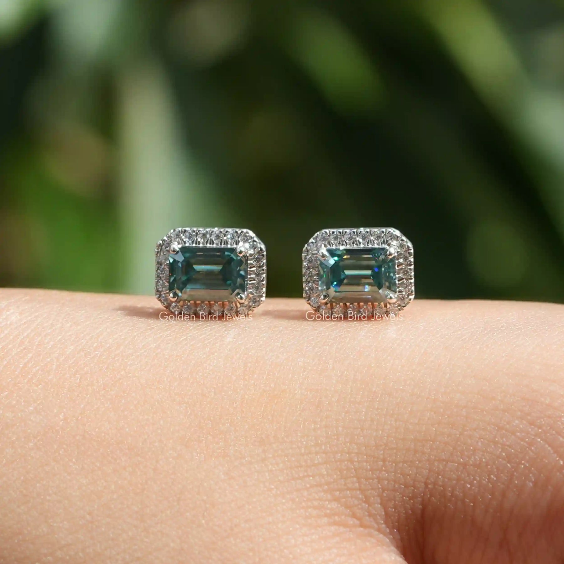 Front view of green emerald cut moissanite earrings in halo style