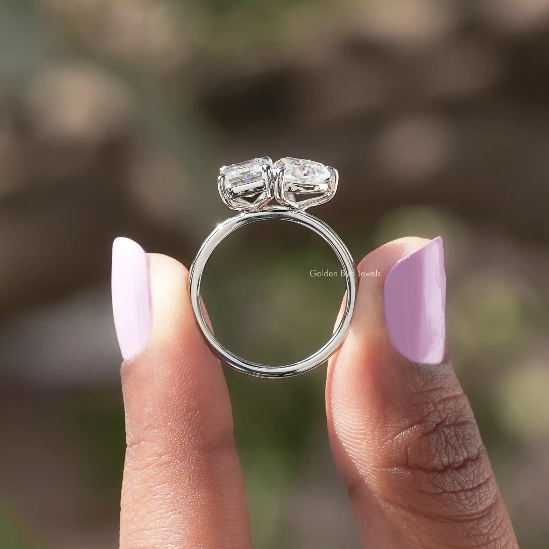 Back view of heart and emerald cut moissanite  ring holding on two fingers