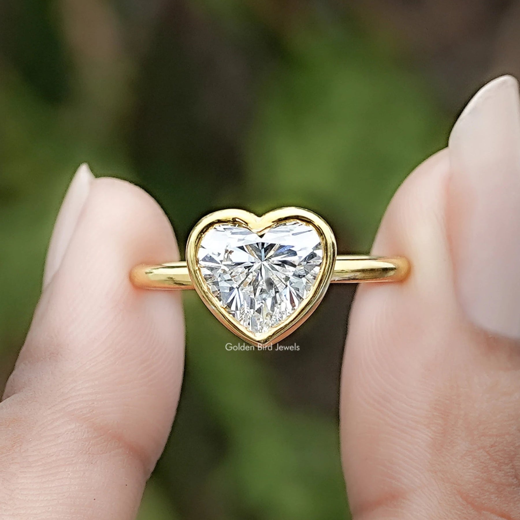 Heart Shaped Lab Diamond Bezel Set Ring Between Two Fingers