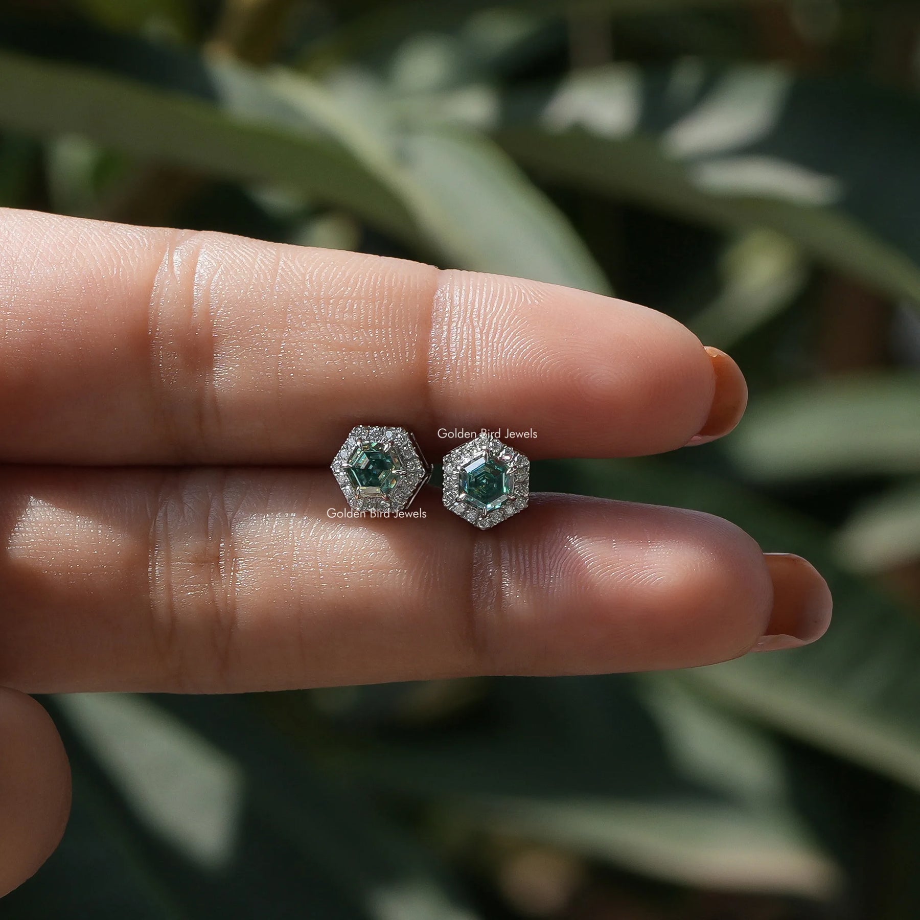 In  two-finger view of halo moissanite stud earings