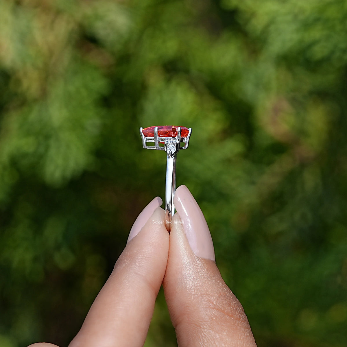 Side View of Kite cut orange sunstone engagement ring In two fingers
