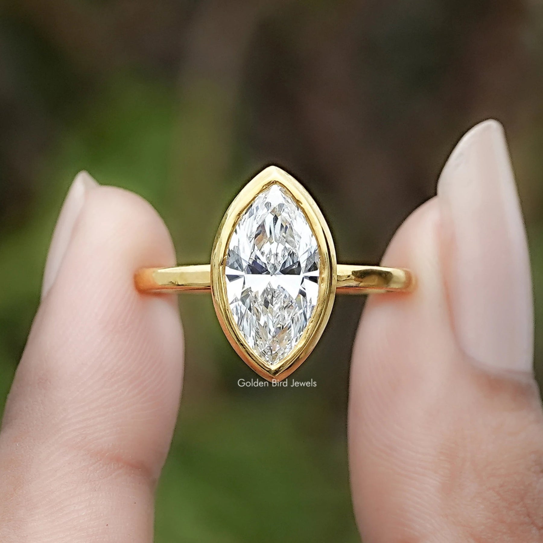 Marquise Cut Lab Diamond Bezel Set Ring Between Two Fingers