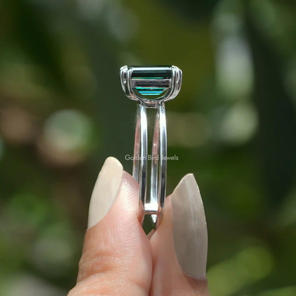 Side View of Moissanite Emerald Cut Solitaire Ring In two fingers