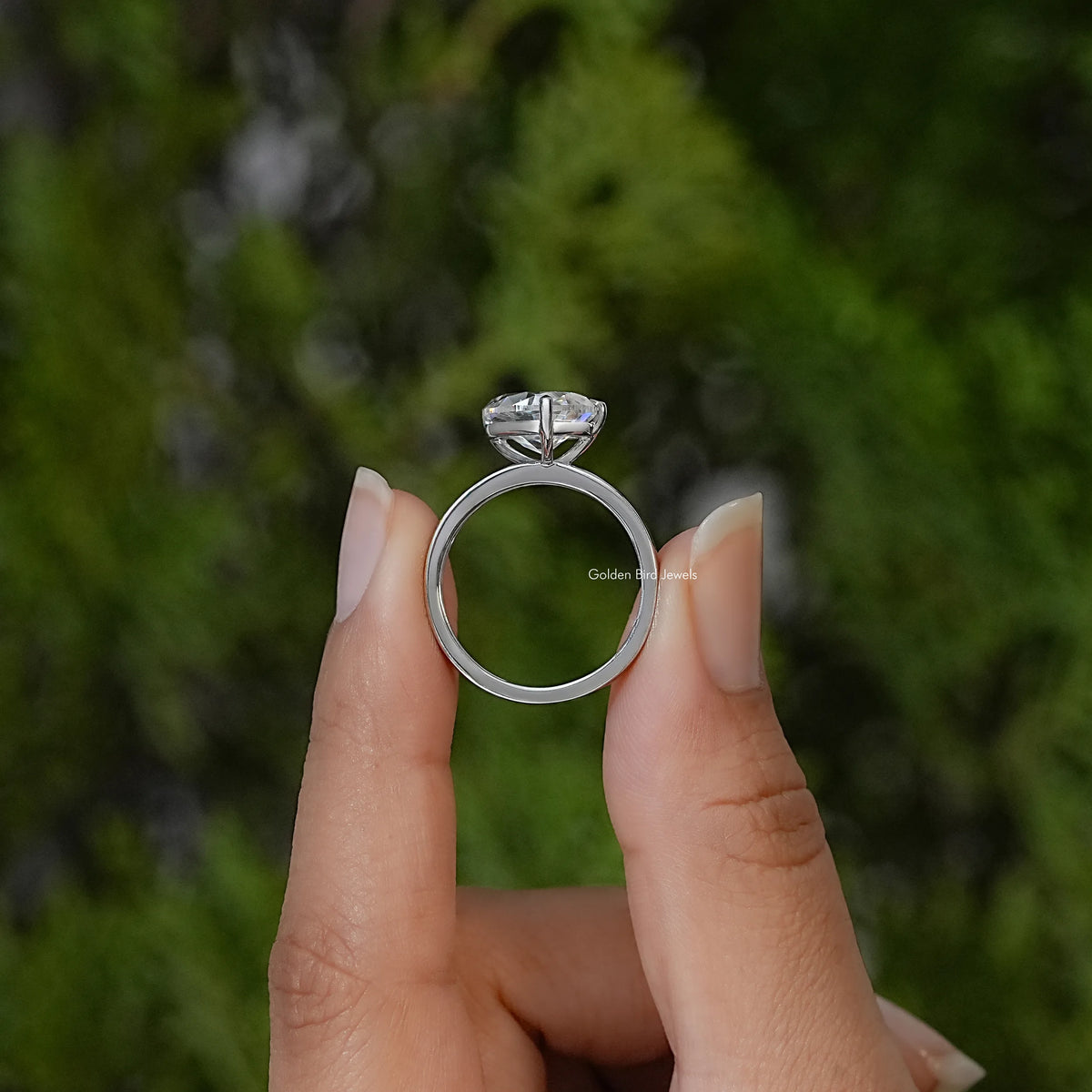 Side view of the silver ring band and raised pear-cut moissanite setting