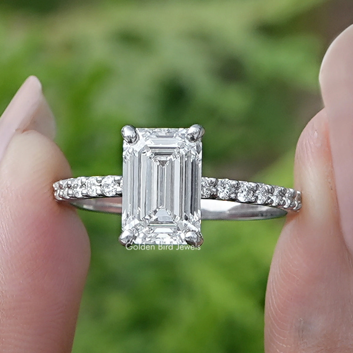 Emerald Cut Diamond Solitaire Ring Held Between Fingers