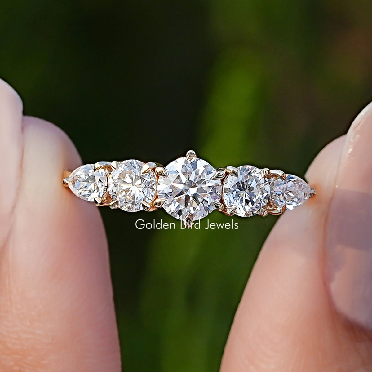 Pear And Round Cut Lab Diamond Five Stone Ring Between Fingers