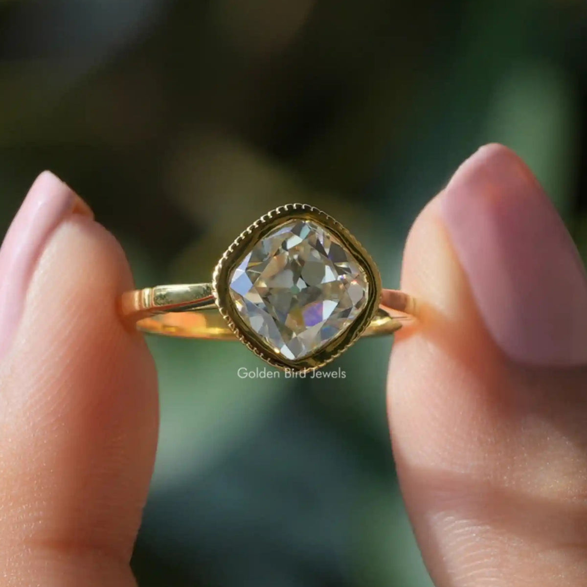 Two fingers holding the Old Mine Cushion Cut Moissanite Ring