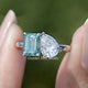 Front view of Pear And Emerald Cut Two Stone Moissanite Ring in two fingers