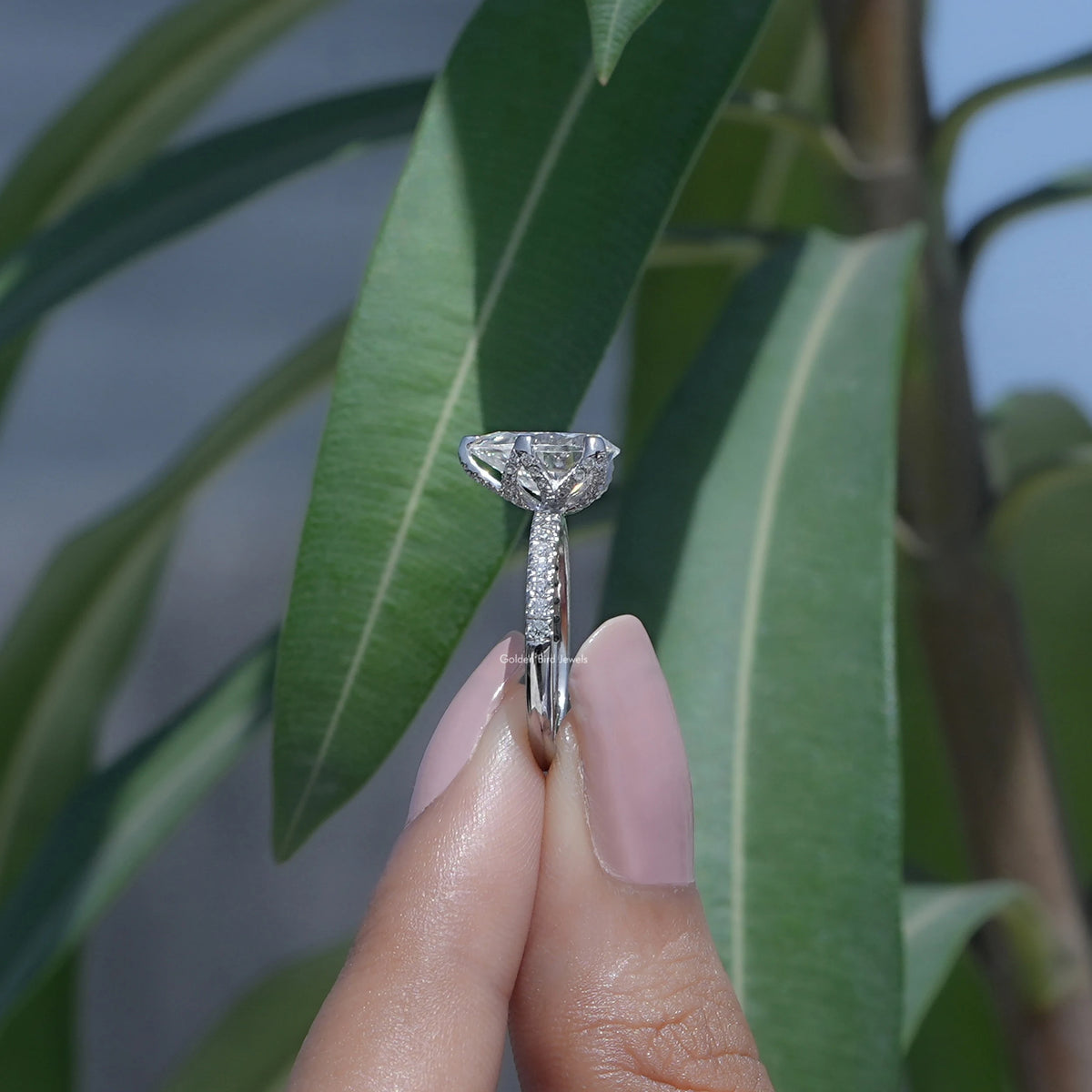 Side View of Pear Cut Moissanite Accent Stone Ring In two fingers