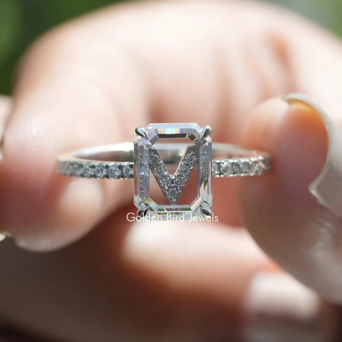 Two fingers holding the Emerald Cut Moissanite Engagement Ring