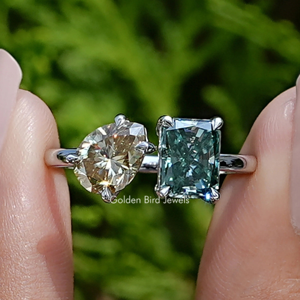 Front view of Radiant And Pear Toi Et Moi Moissanite Ring in two fingers