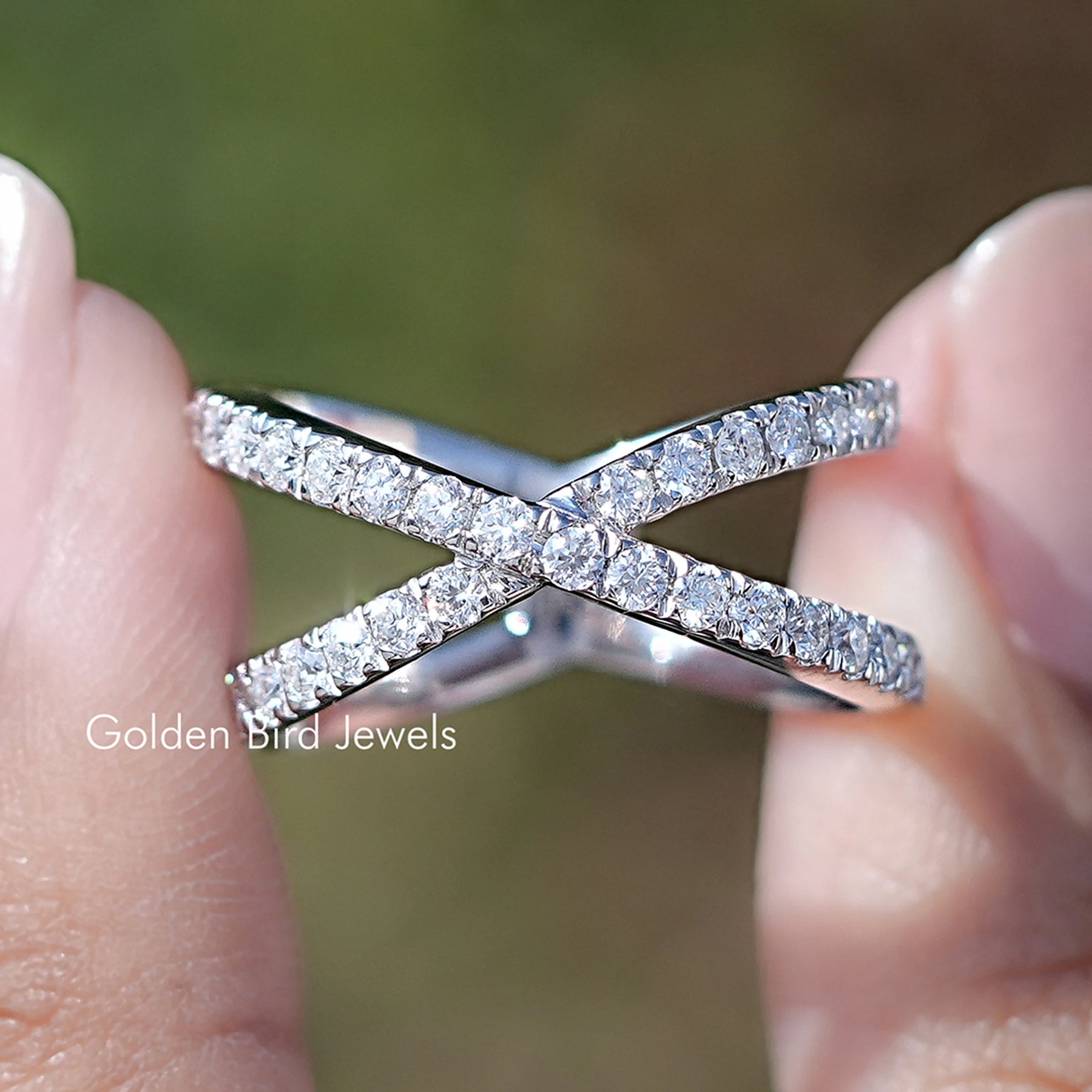 Front view of Round Cut Moissanite Cross Over Engagement Ring in two fingers