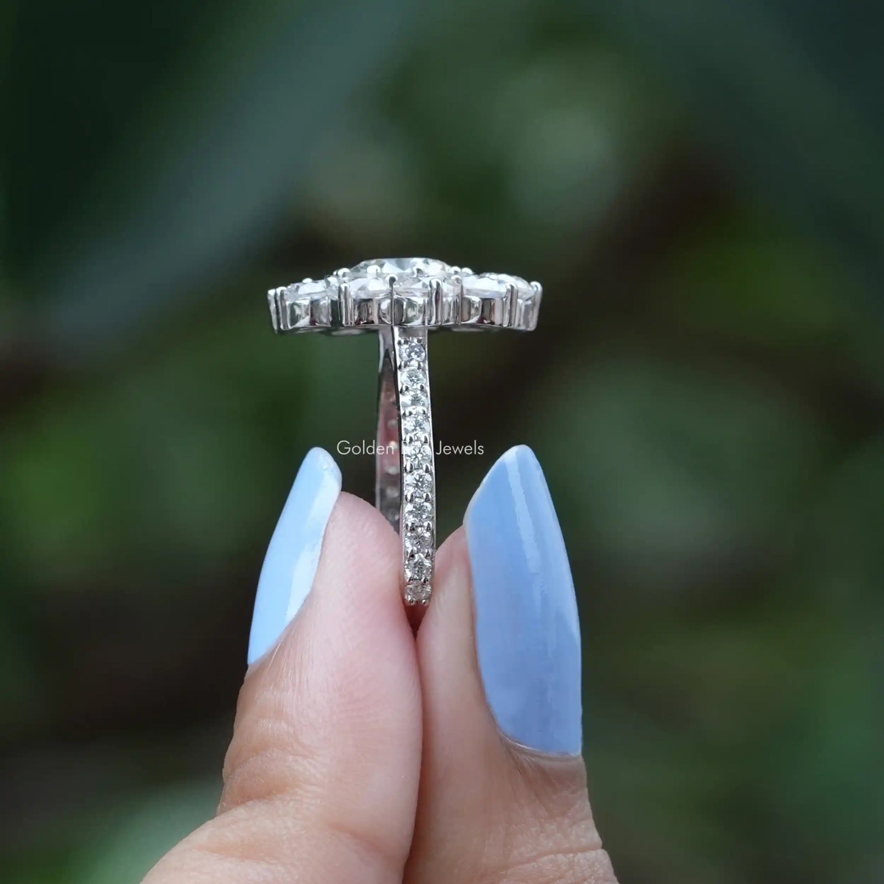 Side View of Round Cut Moissanite Floral Engagement Ring In two fingers