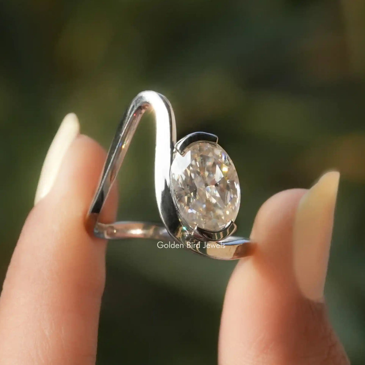 Two fingers holding the Solitaire Oval Cut Moissanite Curved Ring