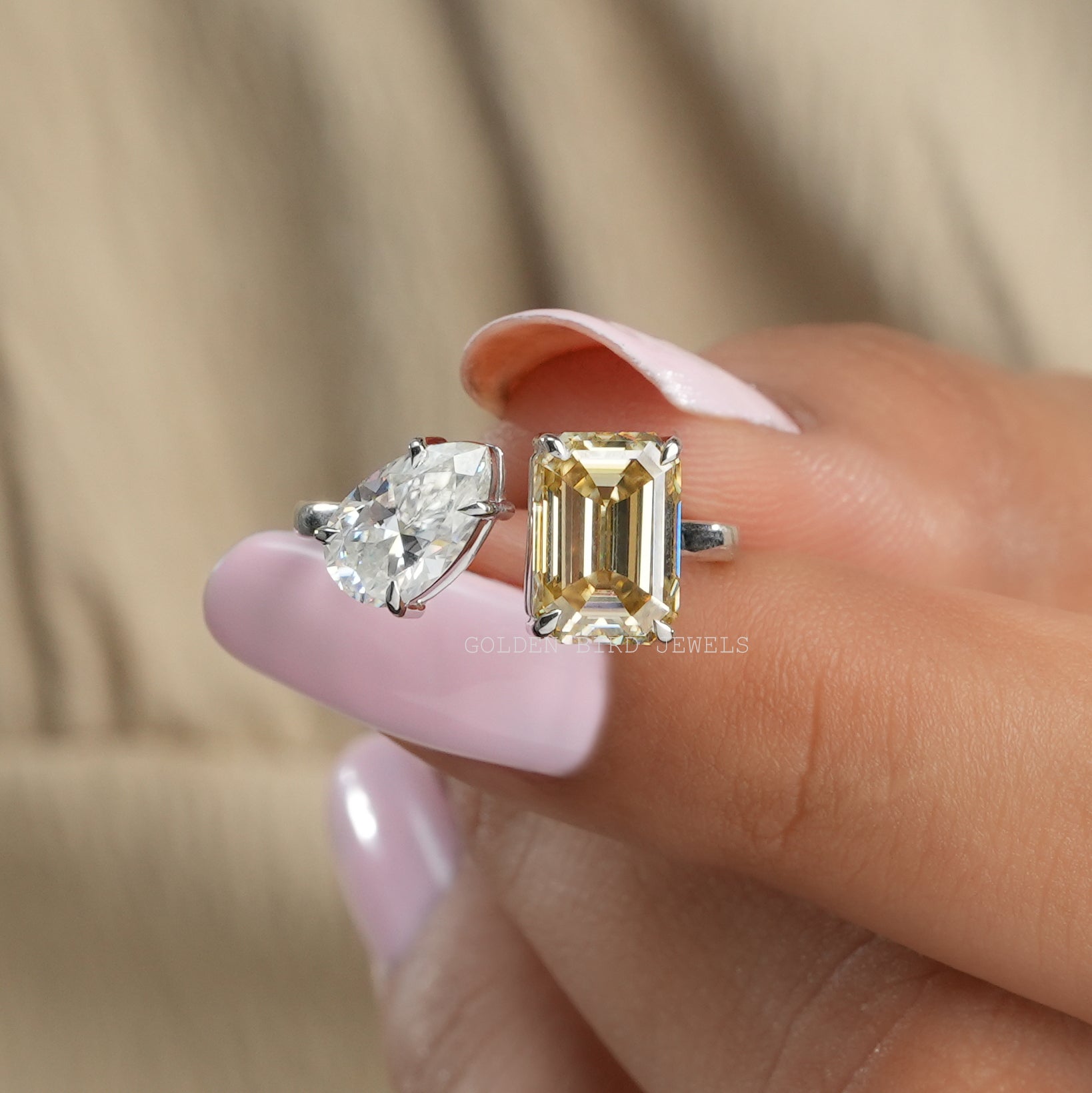 Front View of Emerald Cut Toi Et Moi Moissanite Ring In two Fingers