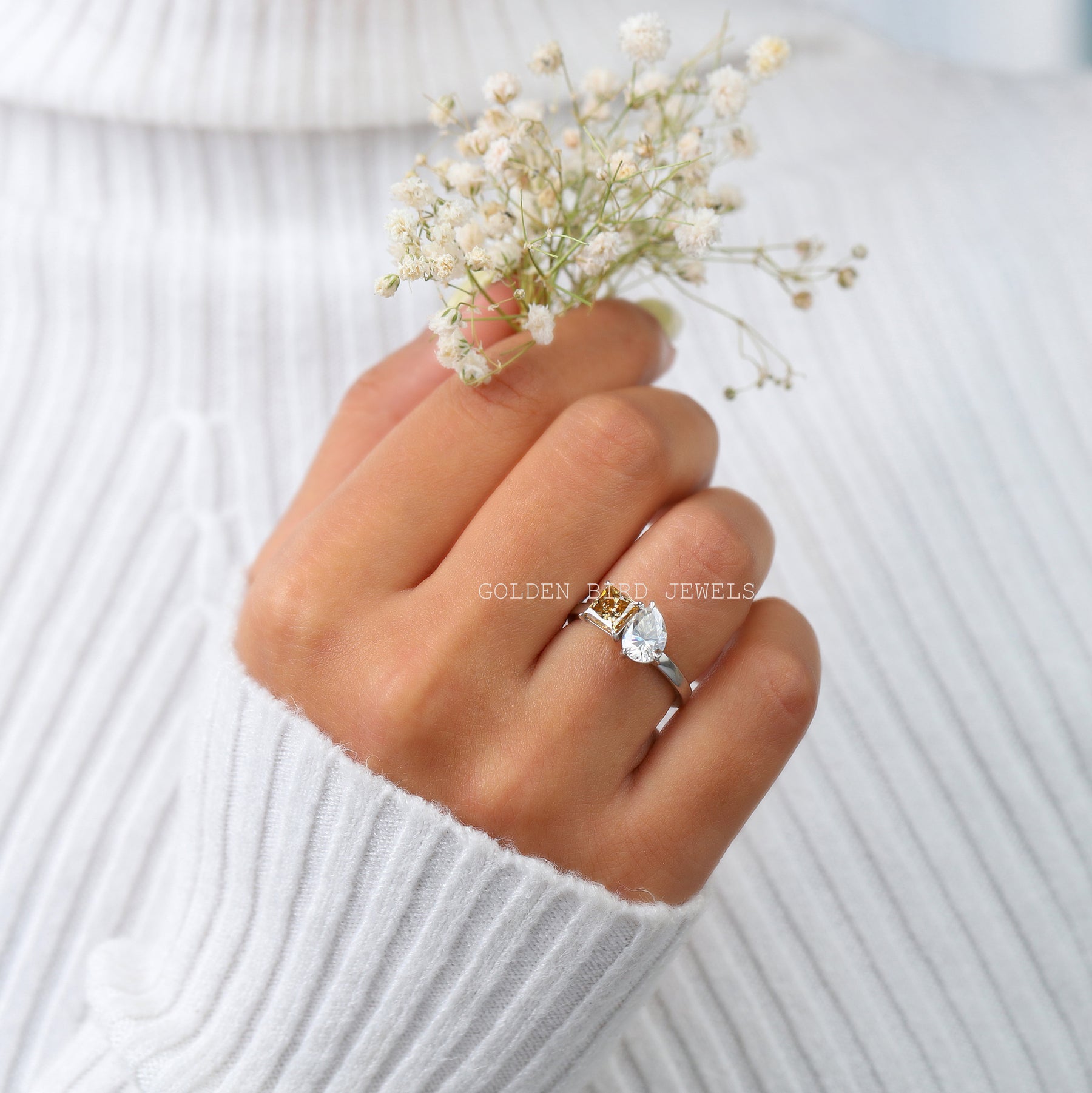 In front finger view of the Toi Et Moi ring in a princess cut and pear-shaped Moissanite stone