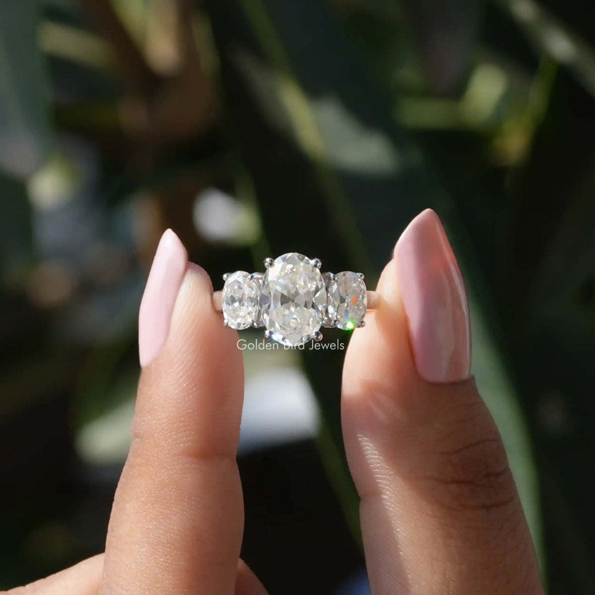 Two fingers holding the Old Mine Oval Cut Three Stone Ring