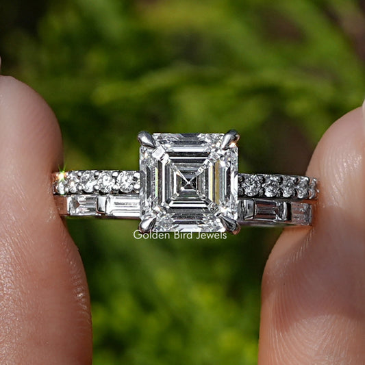 Square Emerald Lab Diamond Wedding Ring Set Held Between Fingers