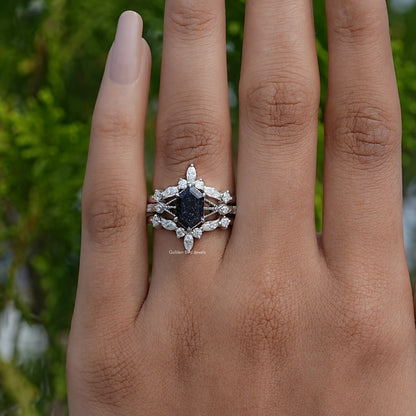 Bridal ring with dark blue hexagon centerpiece and white halo stones on open palm