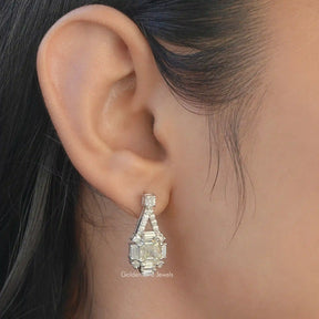 [This asscher cut dangle earrings made of white gold and round cut side stones]