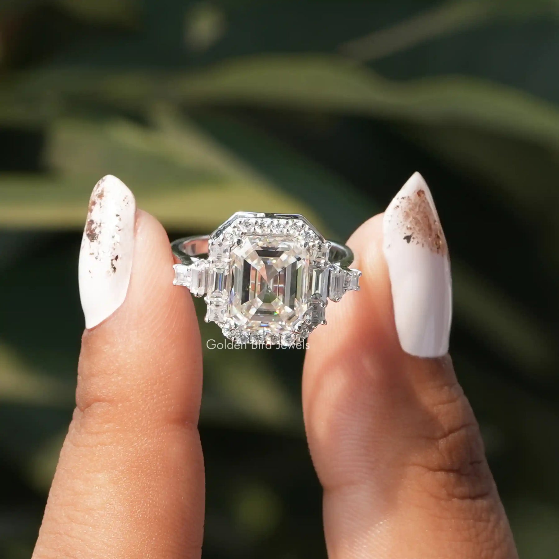 Two fingers holding the Moissanite Asscher Cut Halo Ring