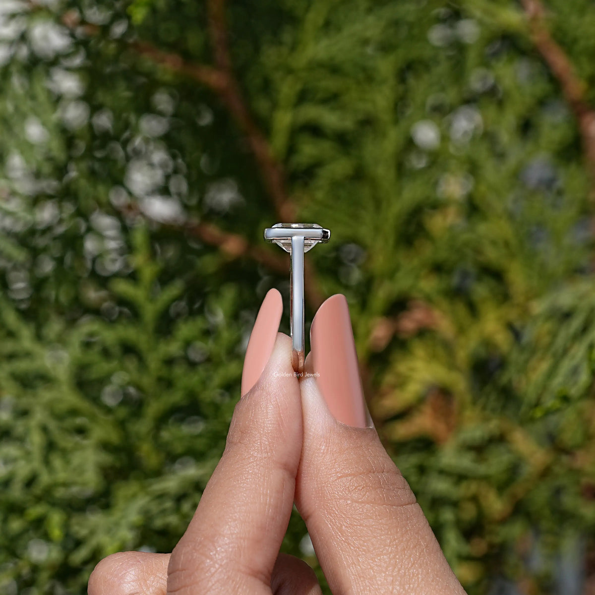 Solitaire emerald-cut moissanite ring with bezel setting, shown in side profile