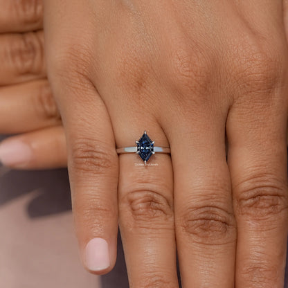 Blue marquise-cut gemstone ring on hand, prong-set silver band