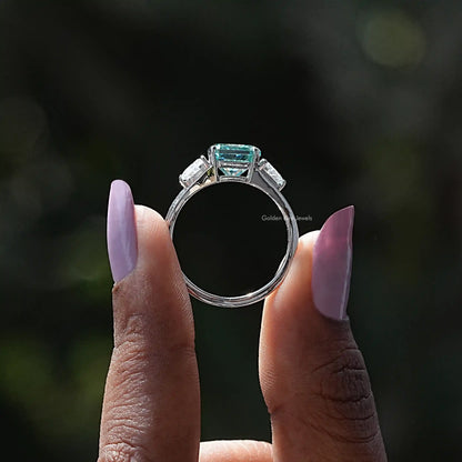 Back View of Blue Radiant Cut Moissanite Three Stone Ring In two fingers