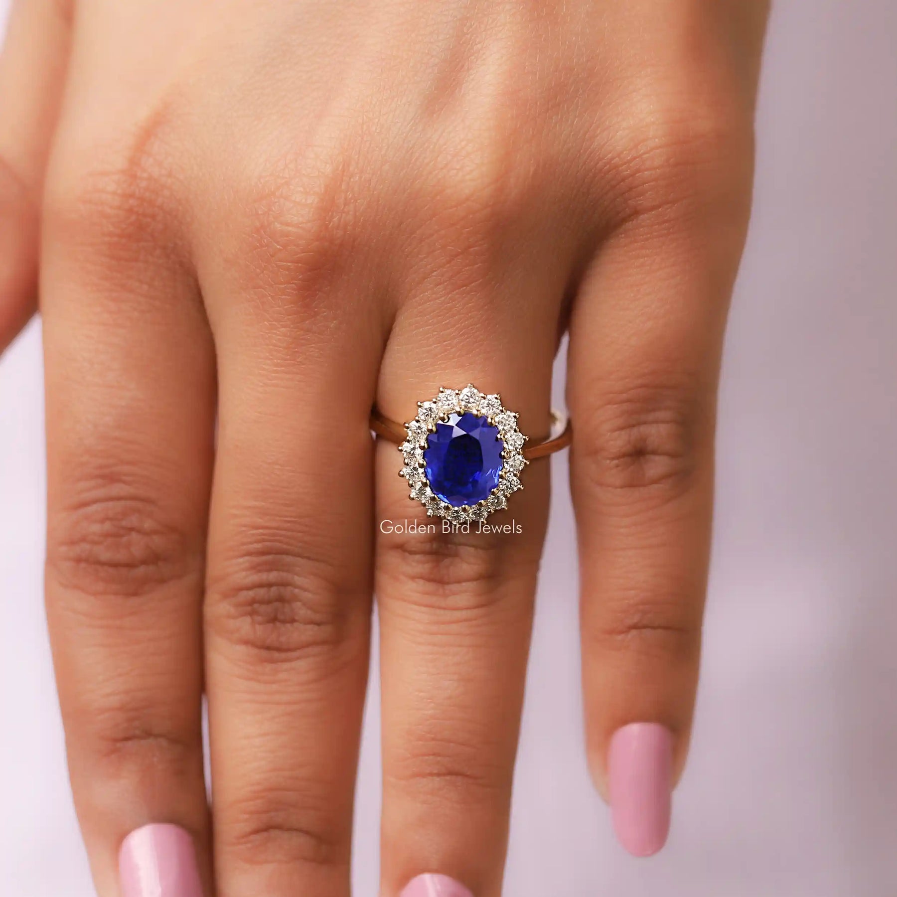 Close View Of Oval Cut Halo Blue Sapphire Ring in a finger