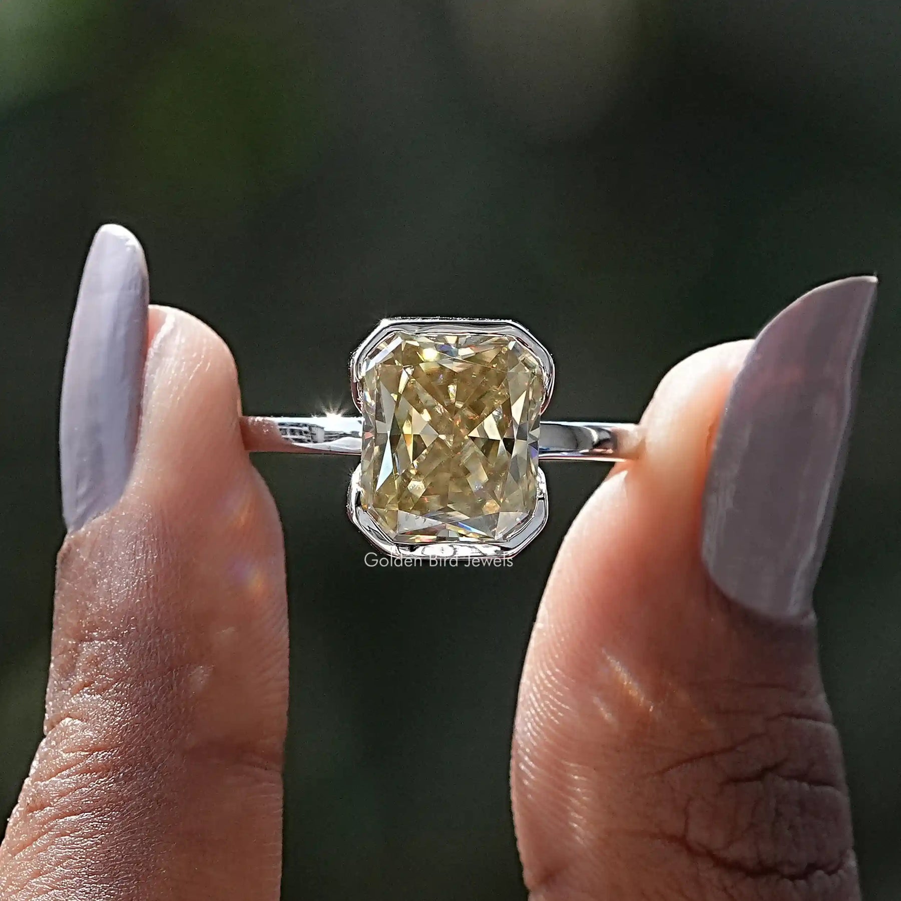 Two fingers holding the Yellow Radiant Cut Moissanite Solitaire Ring