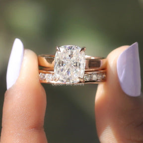 Two fingers holding the Colorless Cushion Cut Moissanite Bridal Ring Set