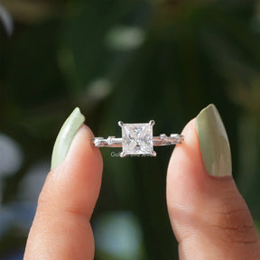 Two fingers holding the Princess Cut Moissanite Solitaire Ring