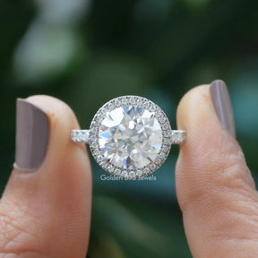 Two fingers holding the Colorless Round Cut Moissanite Halo Ring
