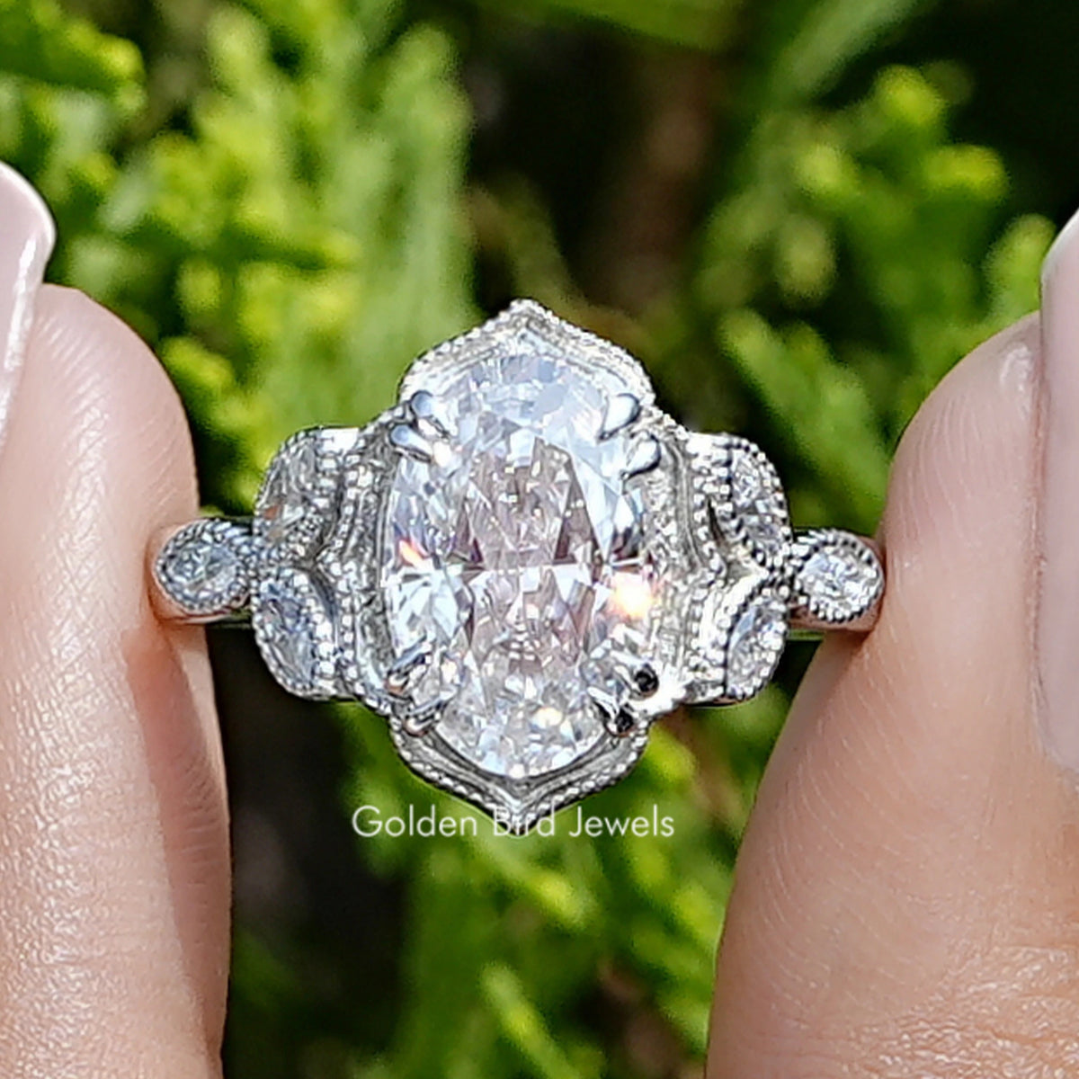 Front view of Crushed Ice Oval Moissanite Milgrain Accent Ring in two fingers 