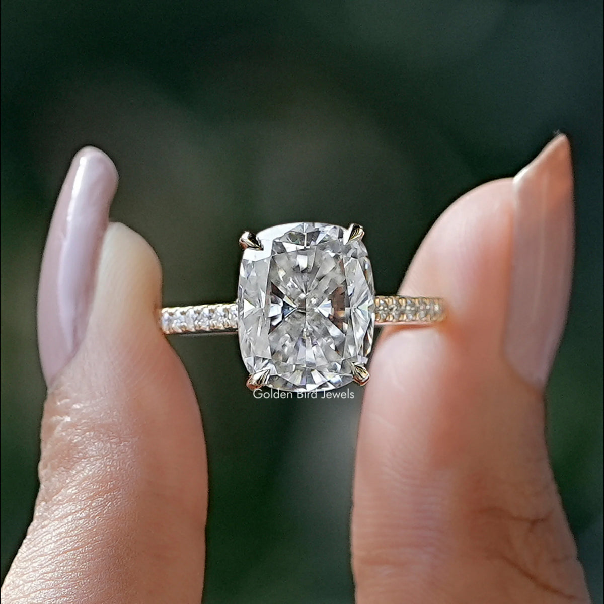 Front view of cushion cut moissanite engagement ring holding in two fingers 