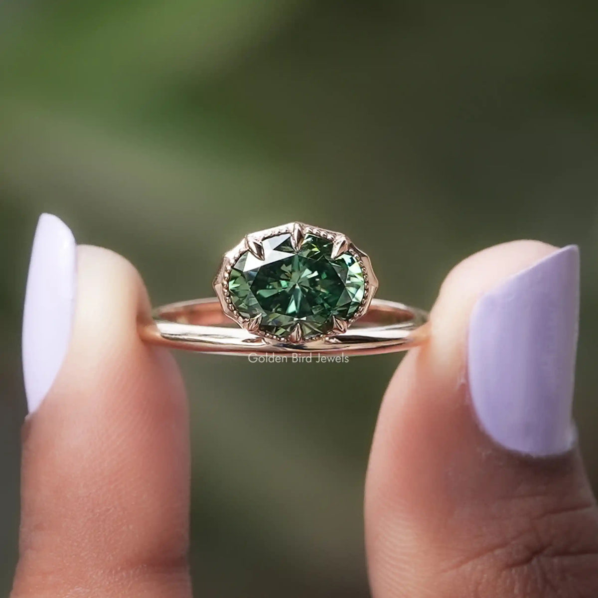 Two fingers holding the Green Oval Cut Moissanite Solitaire Ring