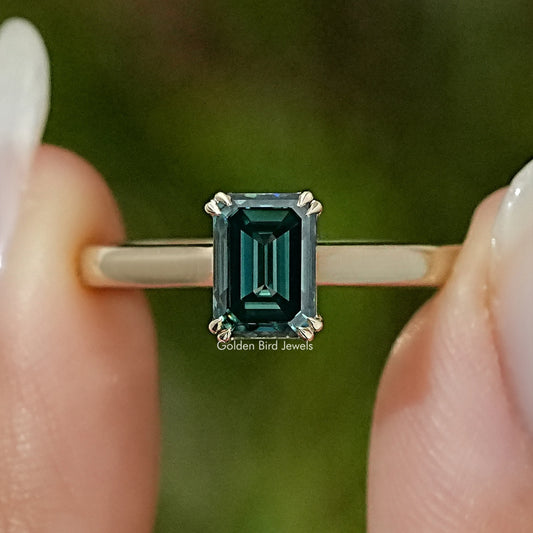 Emerald-cut moissanite engagement ring with dark green stone in four-prong setting