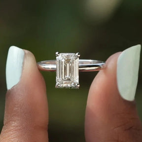 Two fingers holding the Emerald Cut Solitaire Diamond Engagement Ring