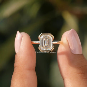 Front View of Bezel Set Emerald Cut Moissanite Engagement Ring In two Fingers