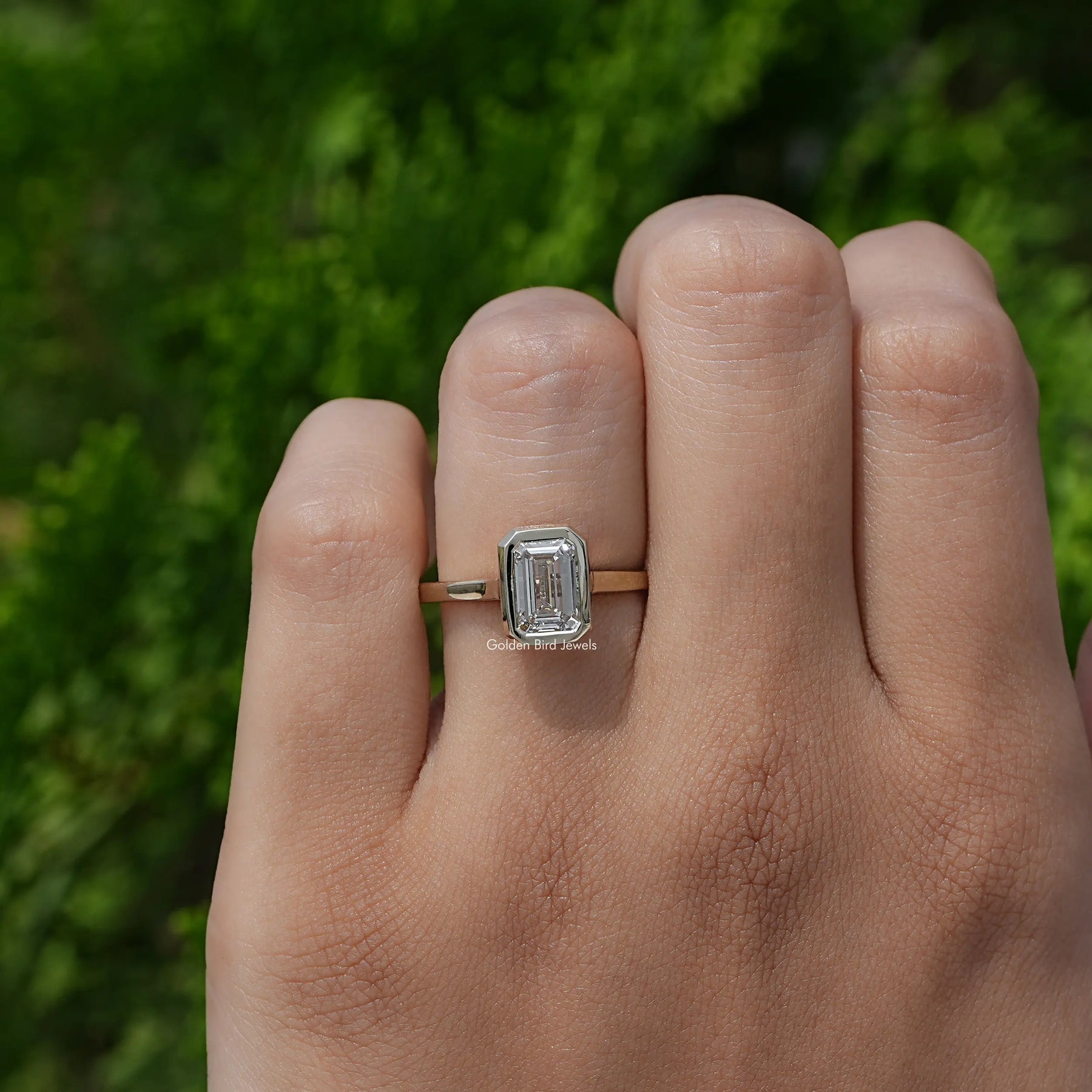 Detailed View of A White Gold Emerald Shaped Ring in a two fingers