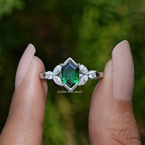 Front View of Green Emerald Hexagon Cut Gemstone Ring In two Fingers