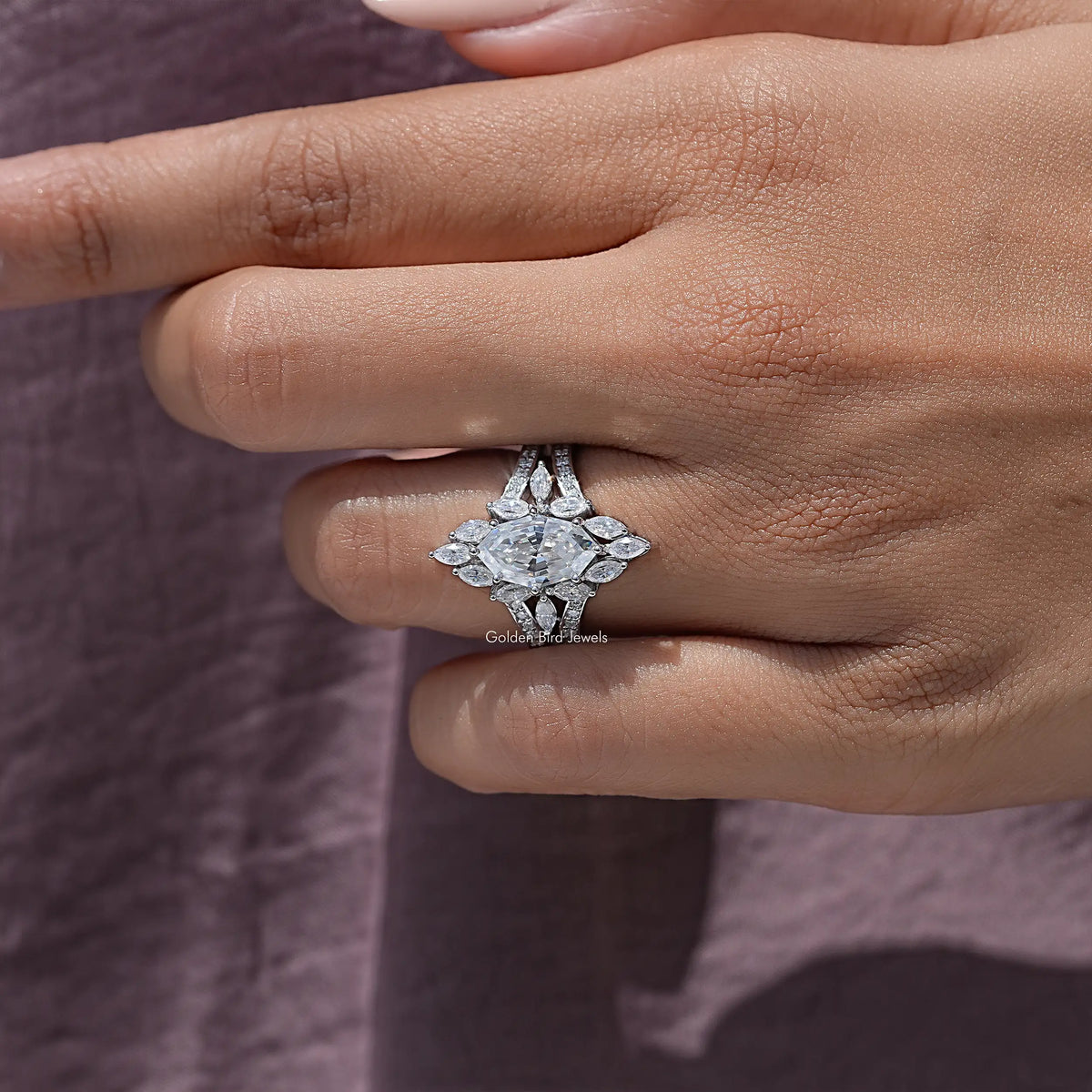 Marquise moissanite halo ring with four-prong center setting, close-up on finger