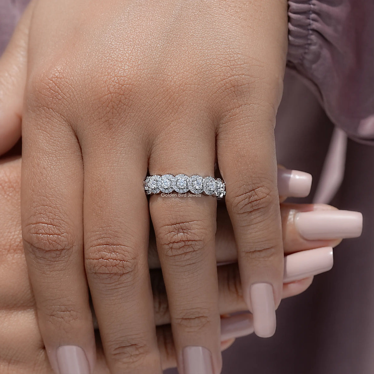 Silver-toned round-stone eternity ring viewed from the front on an open hand