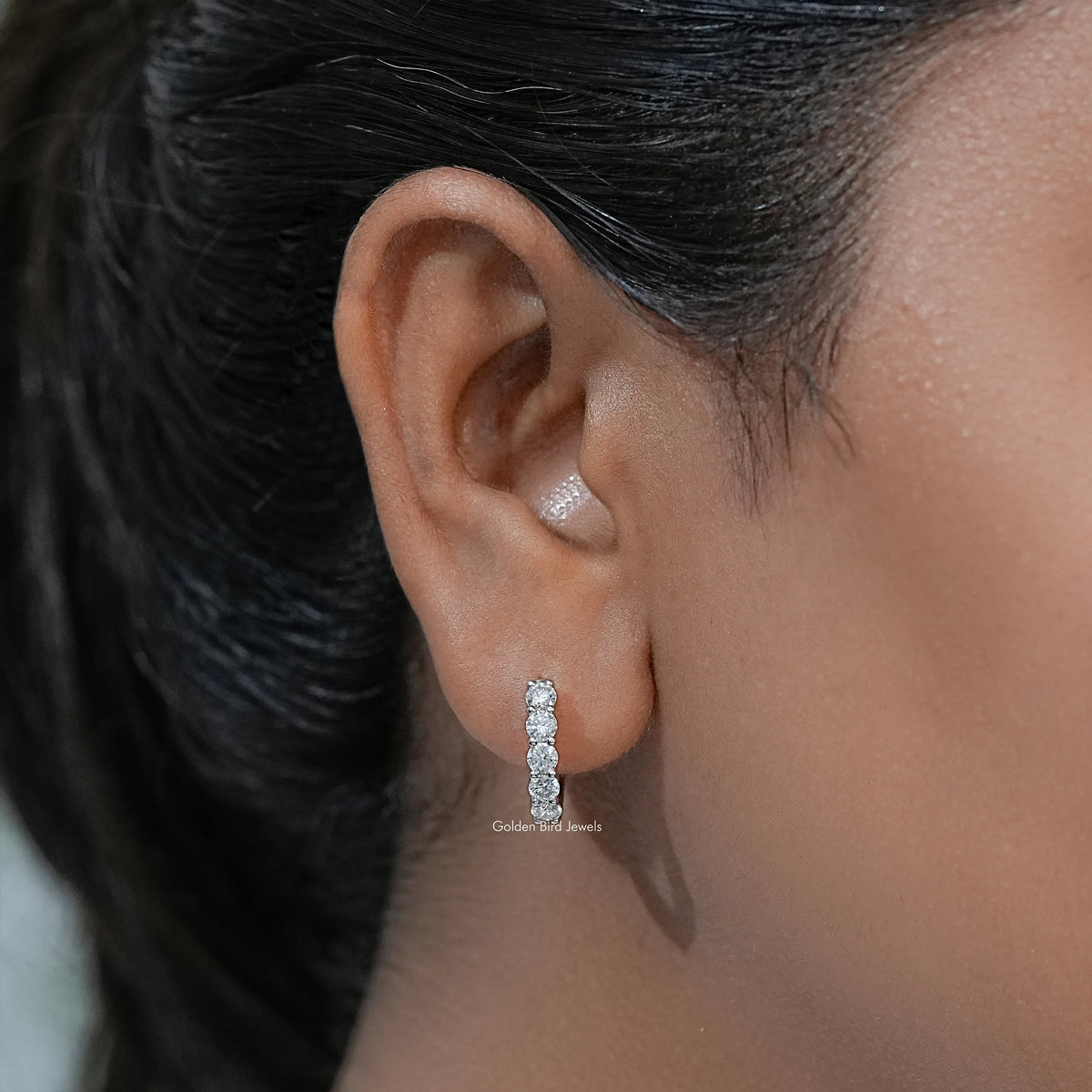 Moissanite round-cut drop earring with pavé stones worn on an ear